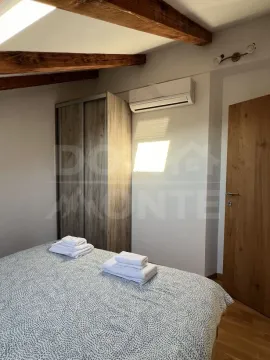Bedroom with a bed, wardrobe, and wooden ceiling beams. - image 10