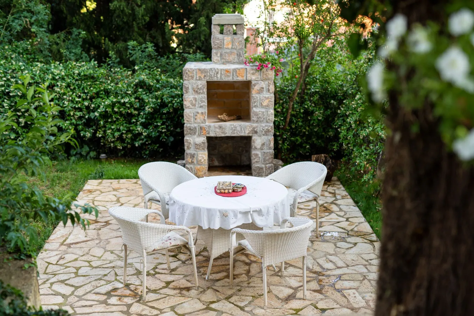 Paved courtyard with outdoor seating and a stone barbecue.