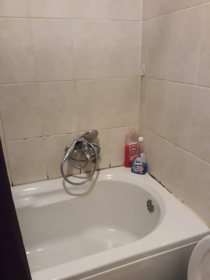A simple white bathtub with ceramic wall tiles.