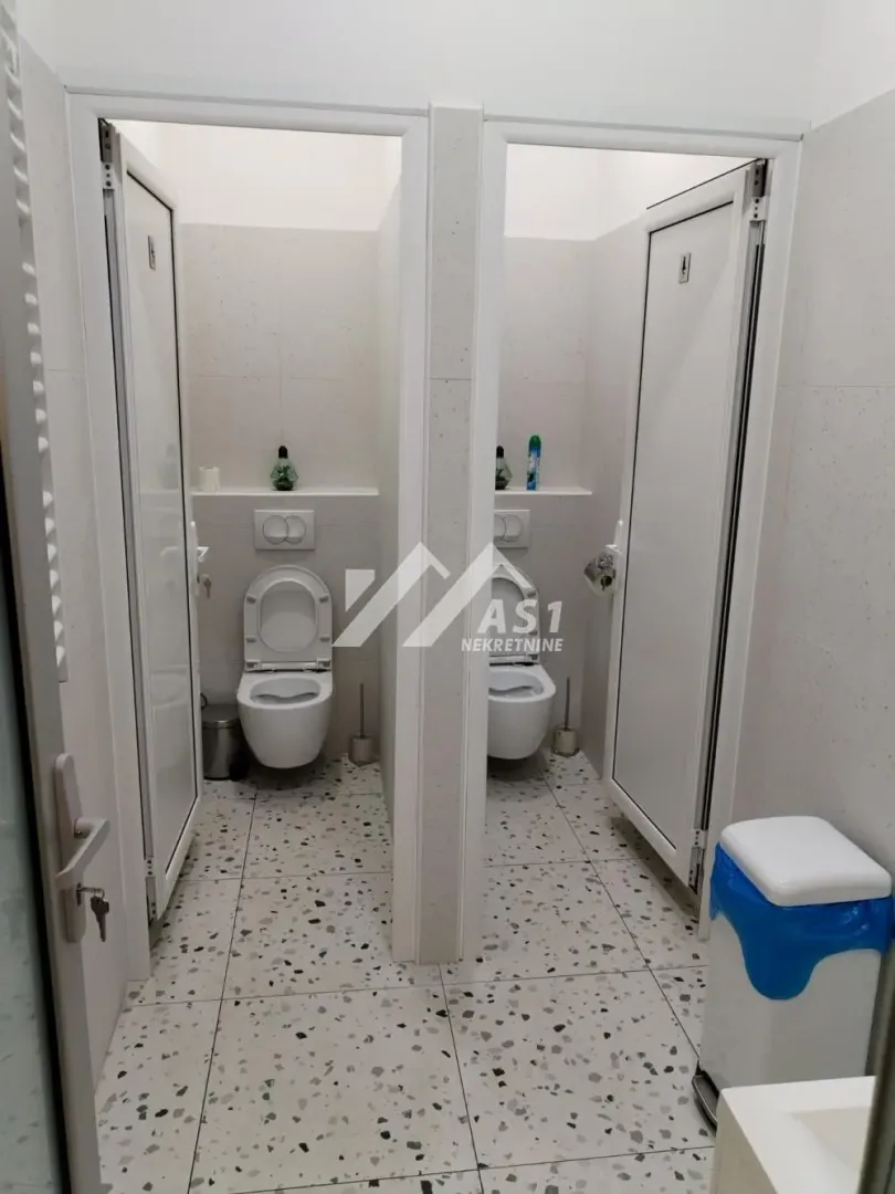 View of separate toilet cabins with white tiles.