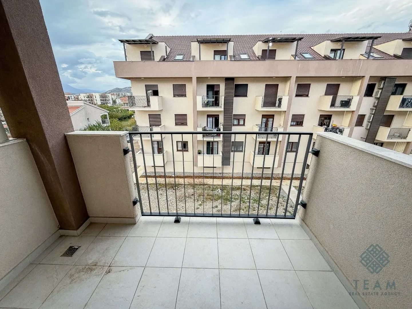 Pogled sa balkona na susjednu stambenu zgradu i okolinu.