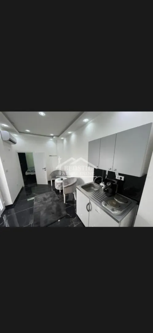 Small kitchen with a sink, electric hob, and upper cabinets.
