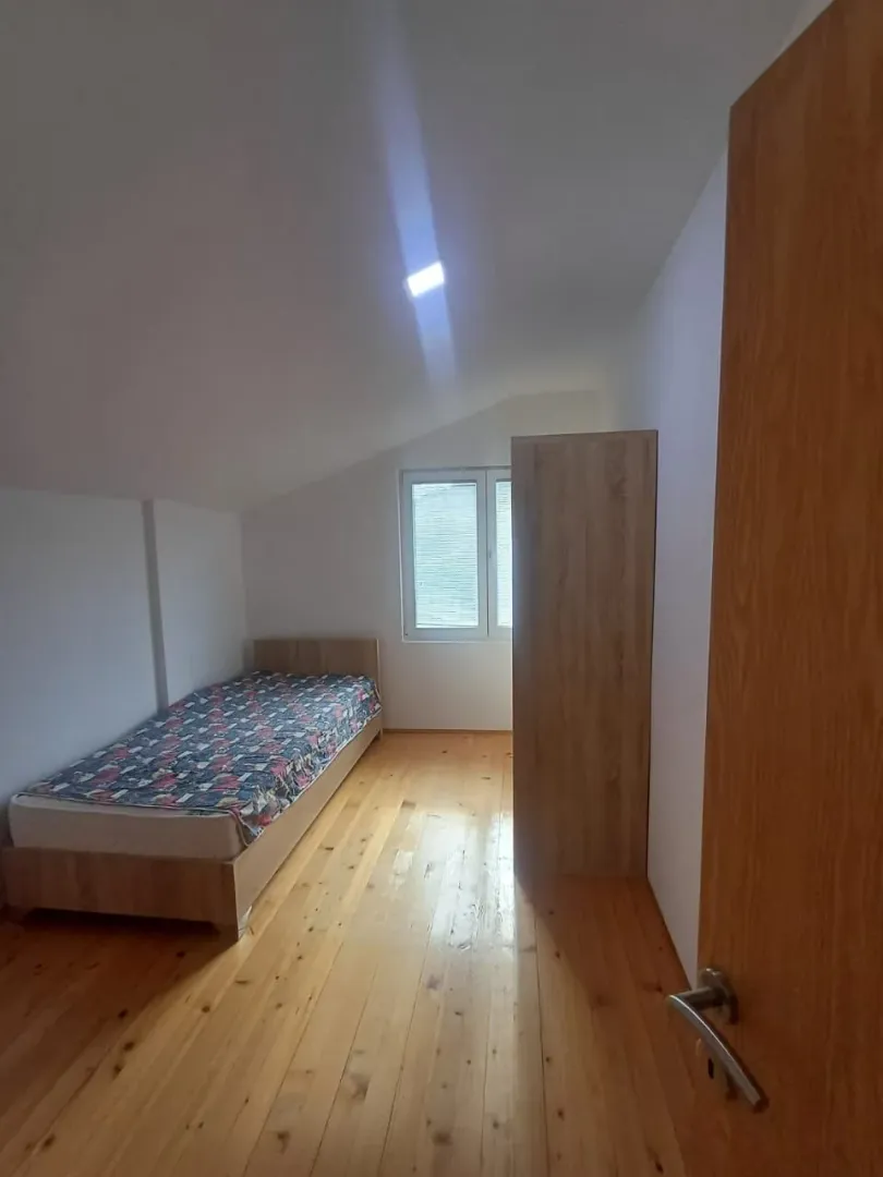 Manja spavaća soba sa krevetom, drvenim podom i ormarom.