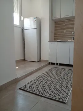 Mala funkcionalna kuhinja sa bijelim elementima i frižiderom. - image 4