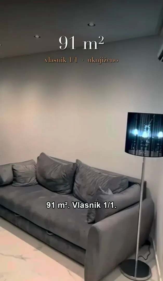Dnevna soba sa sivom garniturom i podnom lampom.
