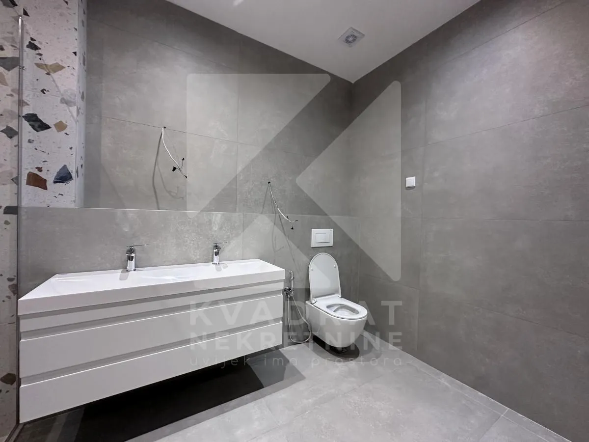 Modern bathroom with gray tiles and a white sink.