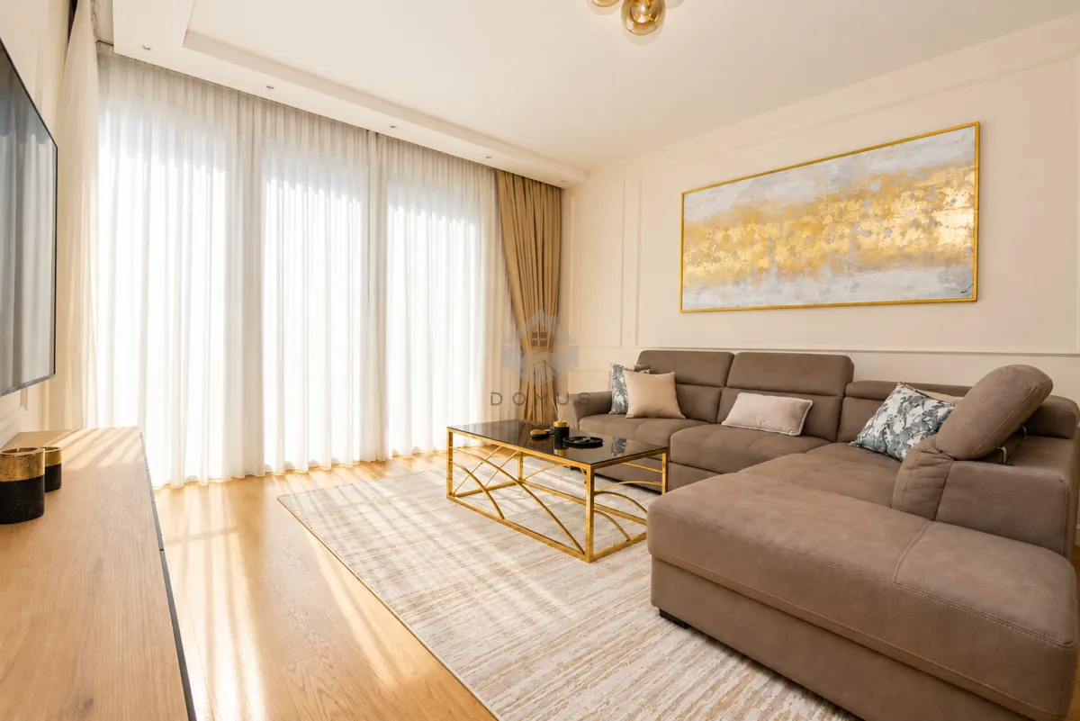 Spacious living room with a sectional sofa, large windows, and a decorative painting on the wall.