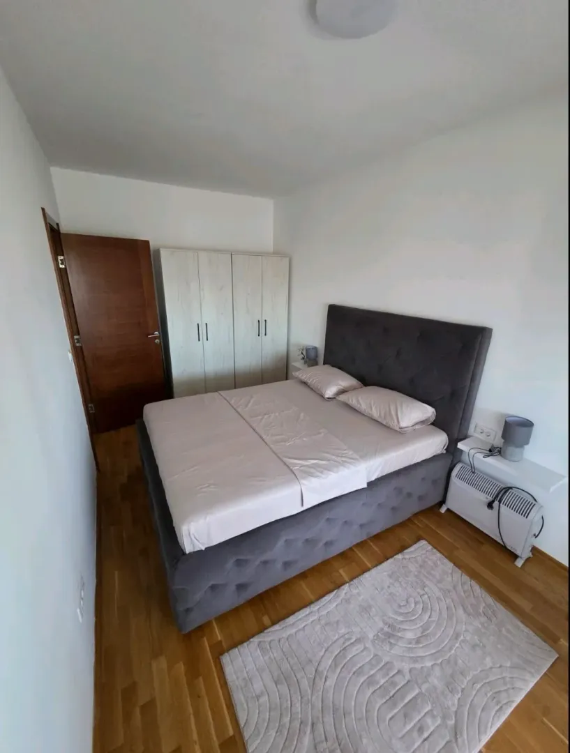 Namještena spavaća soba sa bračnim krevetom, plakarom i laminatom.