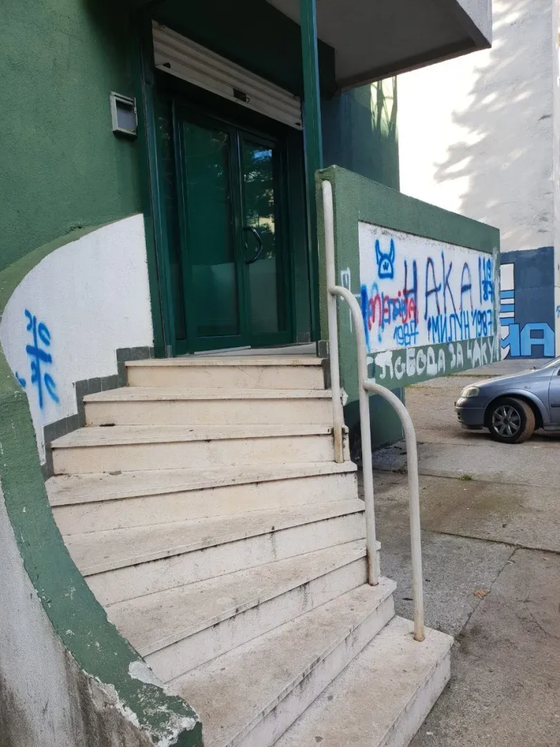 Exterior stairs and entrance to a building with a green facade.
