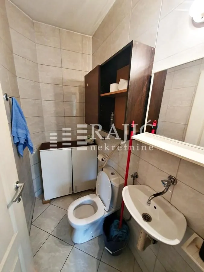 Small bathroom with sanitary fixtures, washbasin, mirror, and cabinet.