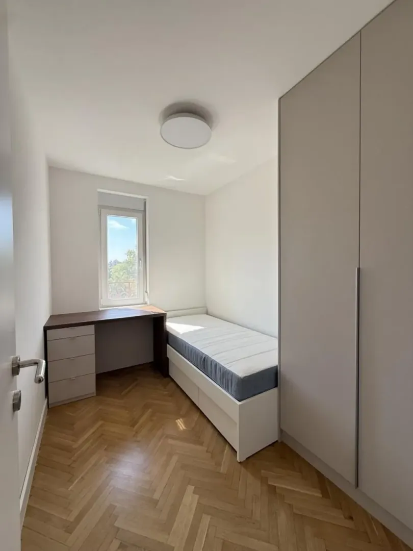 Small bedroom with a bed, desk, and built-in wardrobe.