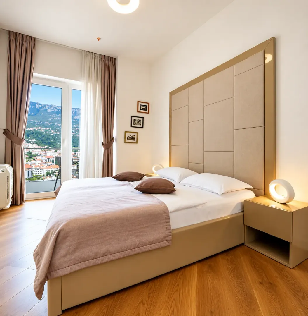 Spacious bedroom with a double bed, large headboard and access to the terrace.