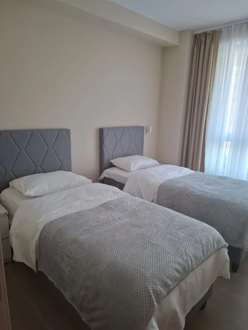 Spavaća soba sa dva singl kreveta i prozorom sa zavjesama.