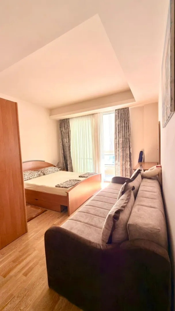 Furnished bedroom with a double bed and a sofa.
