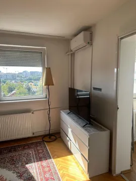 View of a section of the living room with a dresser, television, and air conditioning unit. - image 3