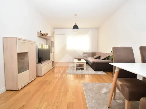 Living room furnished with a sofa, TV, and dining table. - image 11
