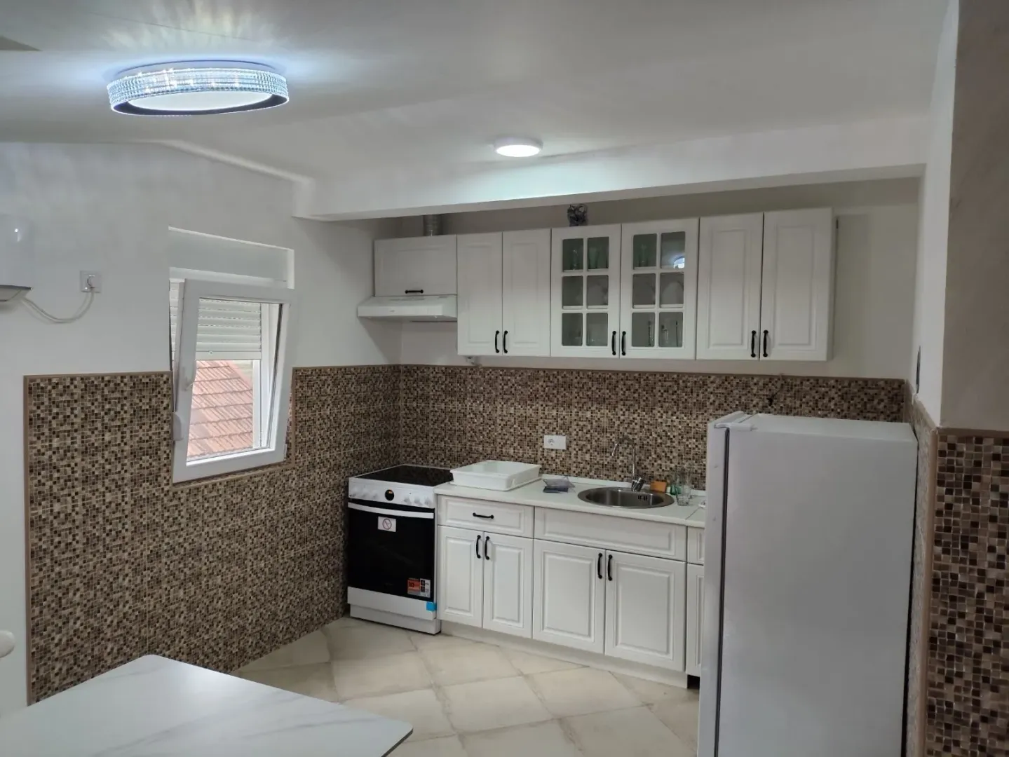Bright and functional kitchen with white cabinets and mosaic tiles.