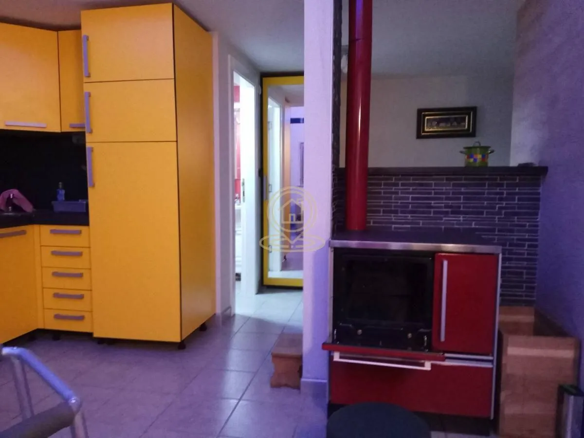 Kuhinja žutih elemenata sa šporetom na drva u uglu.