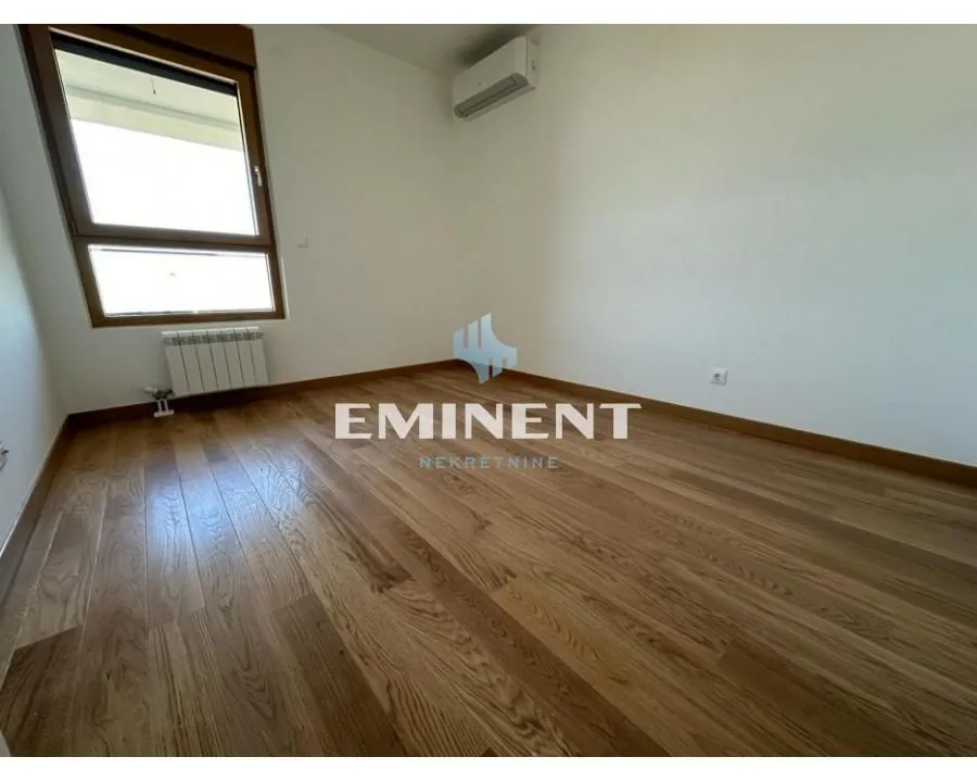Empty room with wooden flooring, a window, and an air conditioning unit.