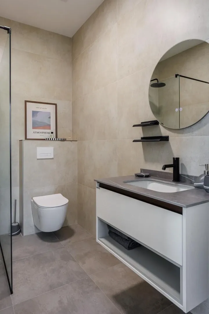 Modernly equipped bathroom with a vanity, walk-in shower, and wall-hung toilet.