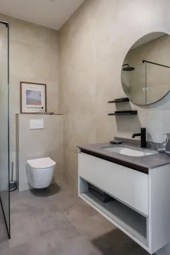 Modernly equipped bathroom with a vanity, walk-in shower, and wall-hung toilet. - image 15