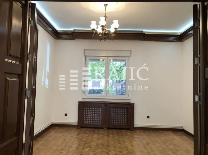 Empty room with wooden flooring, window and chandelier.