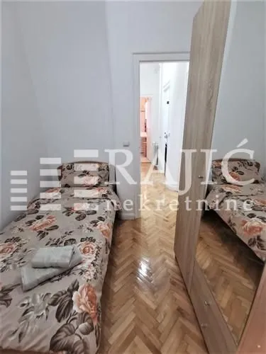 Small bedroom with two single beds and parquet flooring.