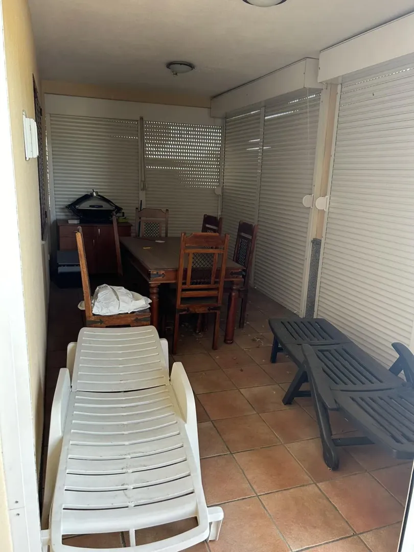 Enclosed terrace featuring a wooden dining table and sun loungers.