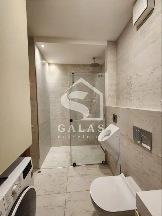 Modernly equipped bathroom with a shower cabin, toilet, and urinal.