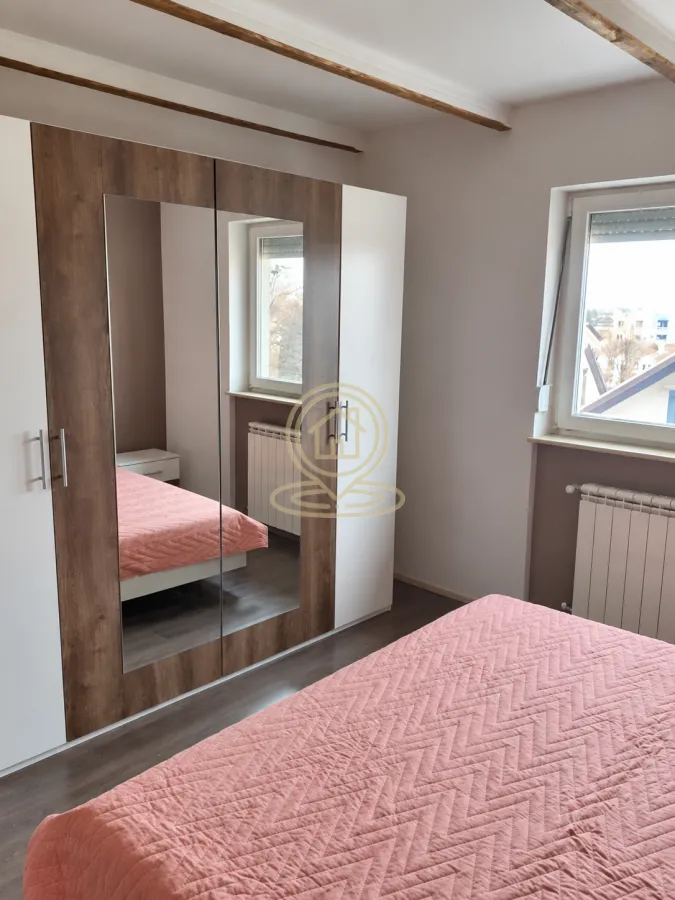 Spavaća soba sa bračnim krevetom, velikim garderoberom sa ogledalom i prozorom.