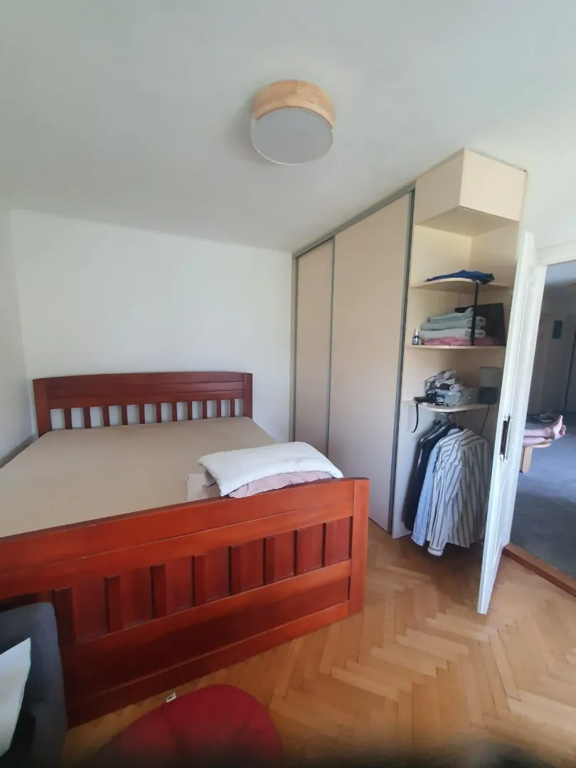 Spavaća soba sa drvenim krevetom i ugradnim ormarom.
