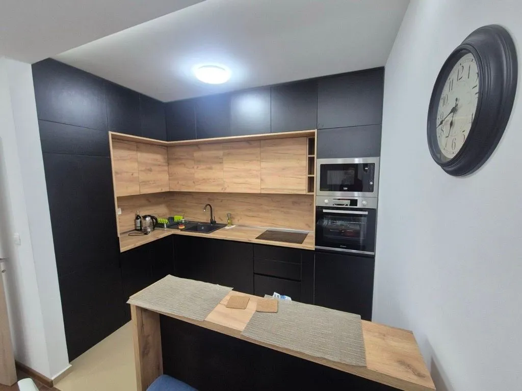Modern dark-toned kitchen with wood accents and a bar counter.