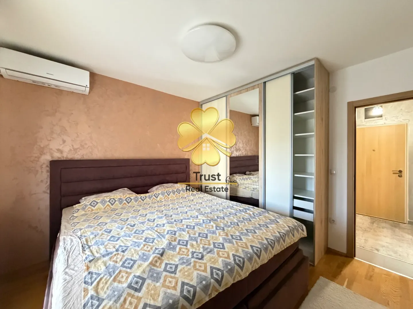 Bedroom with a double bed, large wardrobe, and air conditioning unit.