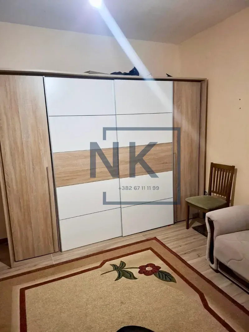 Bedroom with a large wardrobe, bed, and a rug.