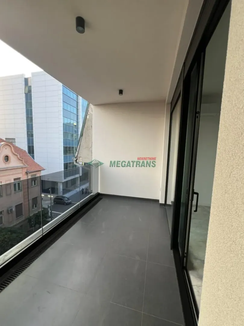 Natkrivena terasa sa staklenom ogradom i pogledom na ulicu.