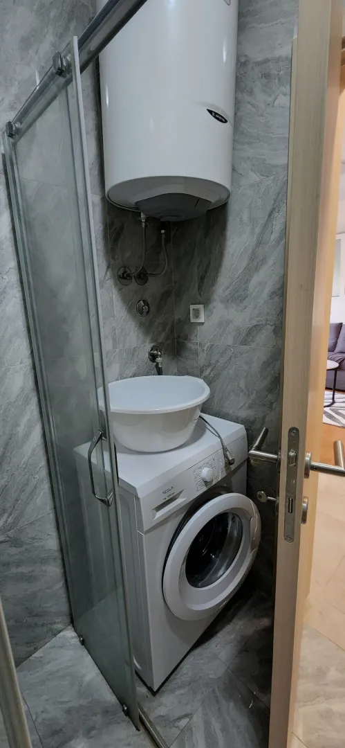 Manje kupatilo sa tuš kabinom, veš mašinom i bojlerom.