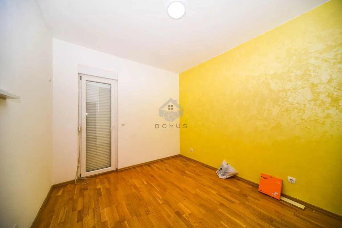Empty room with parquet flooring and one yellow wall.