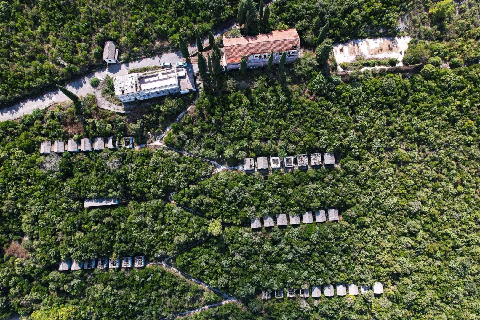 Pogled iz vazduha na imanje sa objektima i šumskim okruženjem.