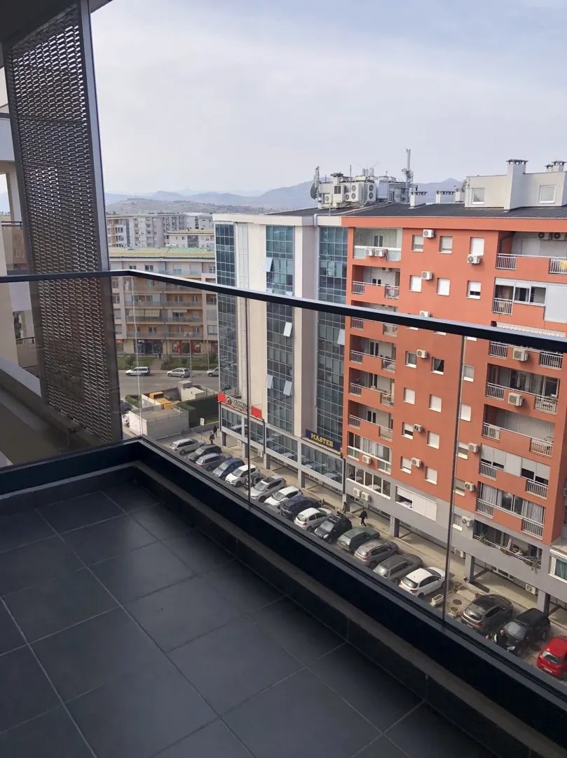 View from the apartment terrace overlooking surrounding buildings and a parking lot.