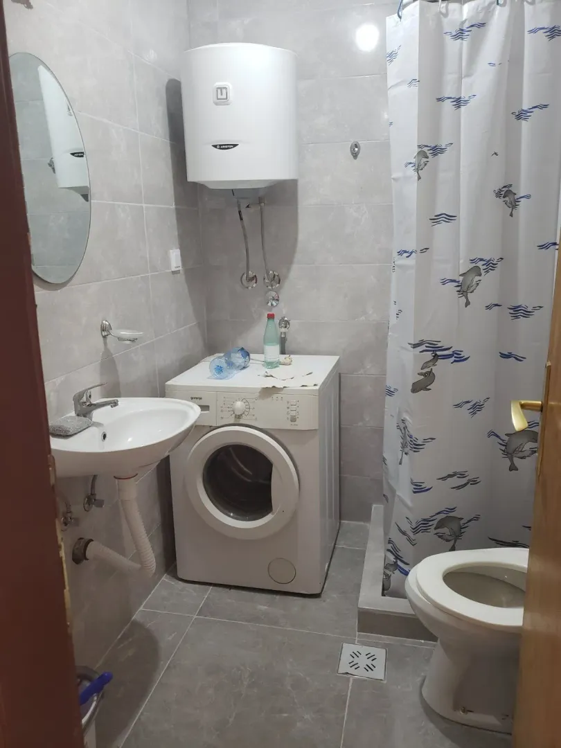 Small bathroom featuring a washing machine, water heater, and a shower with a curtain.
