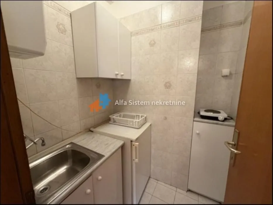 Small kitchen with a sink, refrigerator, and cabinetry.