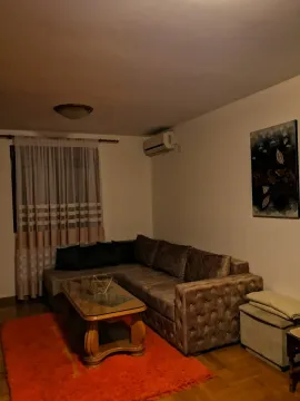 Dnevna soba sa ugaonom garniturom, drvenim klub stolom i narandžastim tepihom. - image 7