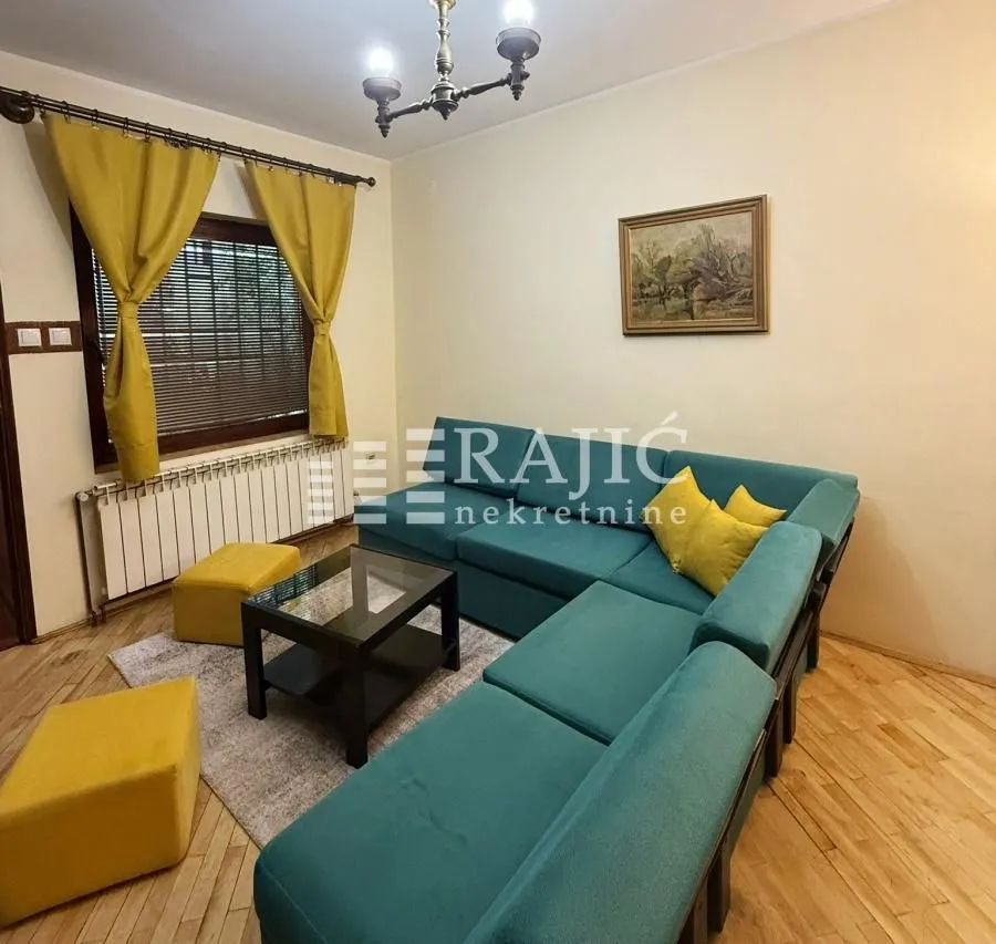 Living room with a turquoise sectional sofa, coffee table, and yellow accents.