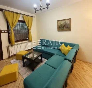 Living room with a turquoise sectional sofa, coffee table, and yellow accents. - image 2