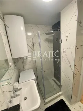 Modern bathroom with a walk-in shower, washbasin, and water heater. - image 10