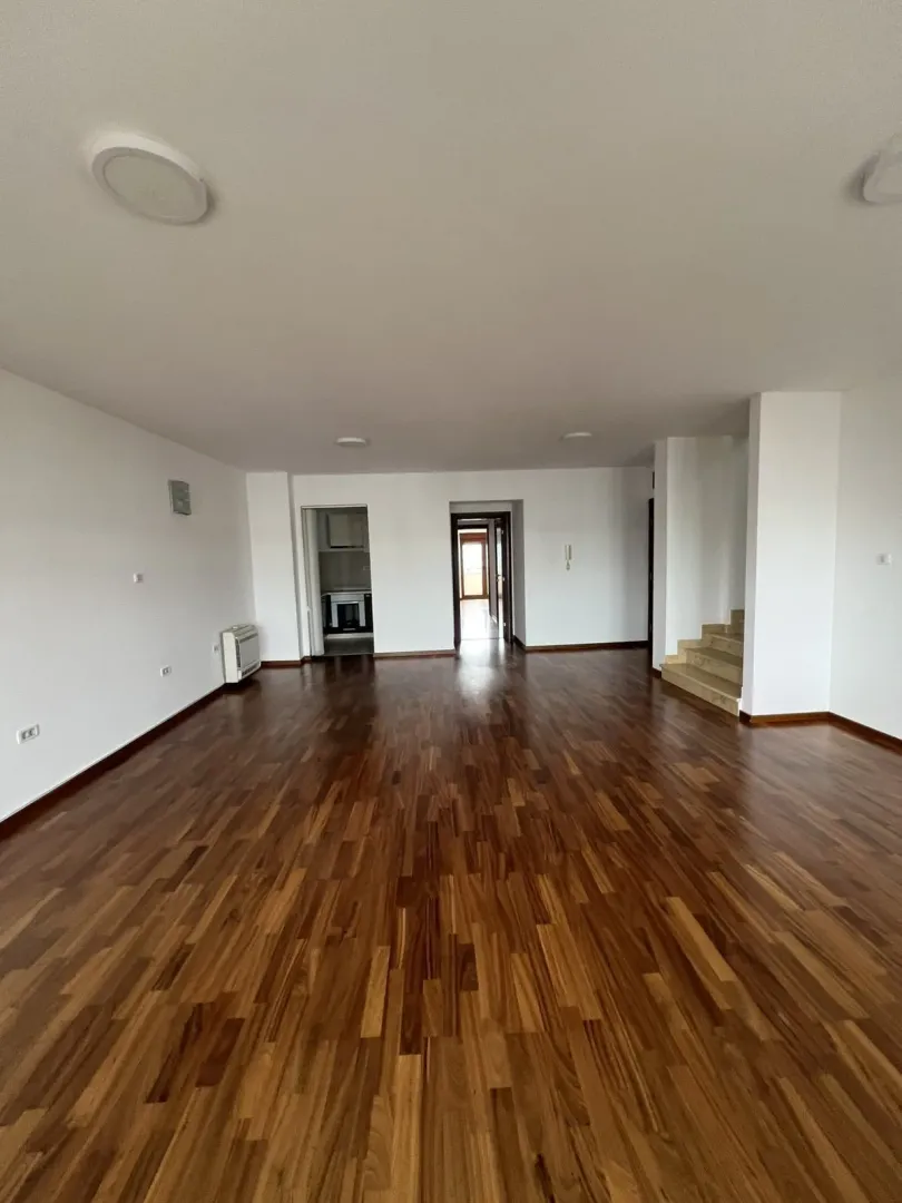 A spacious empty room with wooden flooring.
