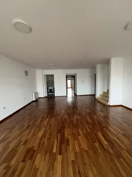 A spacious empty room with wooden flooring. - image 2