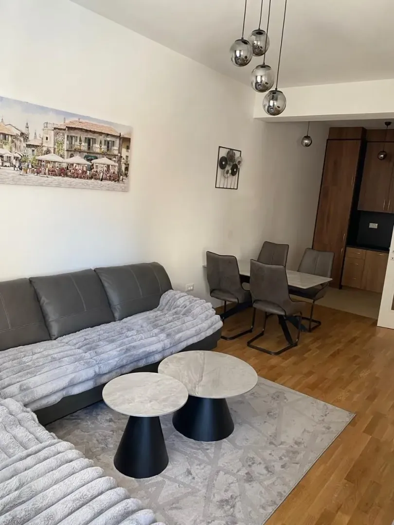 Living room with sofa, dining area, and view of the kitchen.