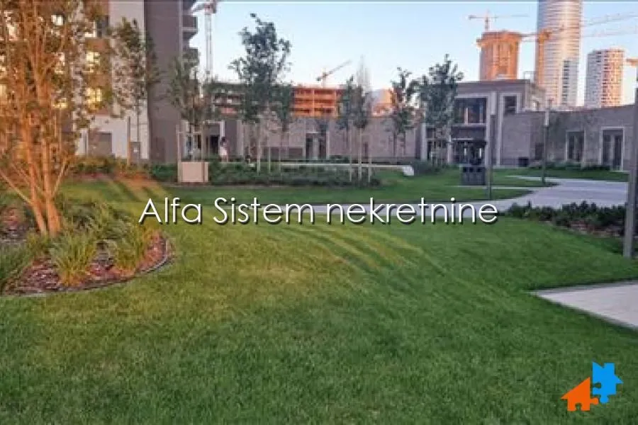 Uređeno dvorište i zelene površine ispred stambenih zgrada.