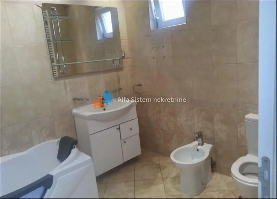 Tiled bathroom equipped with a bathtub, washbasin, and sanitary fixtures.